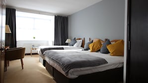 A hotel room with two beds, a desk, and a chair.