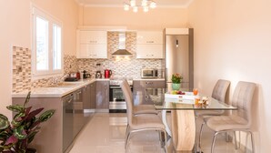 Una cocina moderna con una mesa de comedor de vidrio, electrodomésticos de acero inoxidable y un salpicadero de azulejos.
