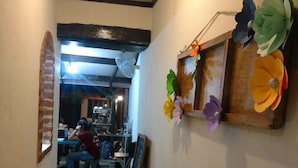 A hallway with a wooden bench, a glass table, and a wall decorated with paper flowers. - Hostal Tía Mema (Santa Ana)