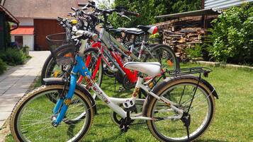 Una hilera de bicicletas estacionadas en un césped, con una casa y un cobertizo al fondo.