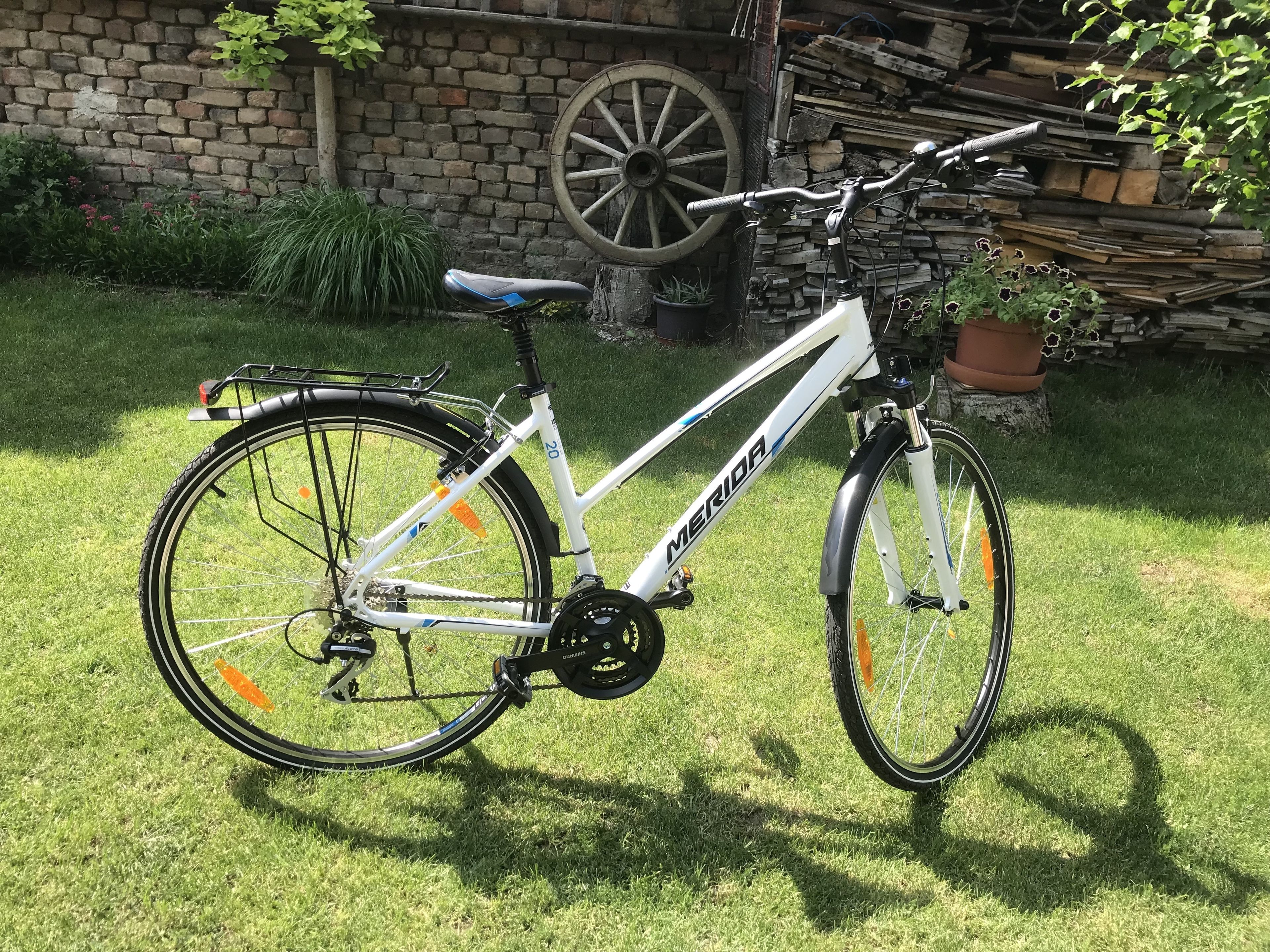 Ein weißes Fahrrad mit dem Markennamen 'MERIDA' steht auf einer Rasenfläche.