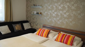 Una habitación de hotel con una cama, un sofá negro y una pared con papel tapiz floral.