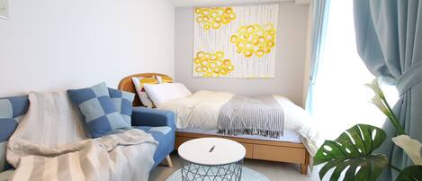 A modern bedroom with a bed, a sofa, a round side table, and a large window with curtains.