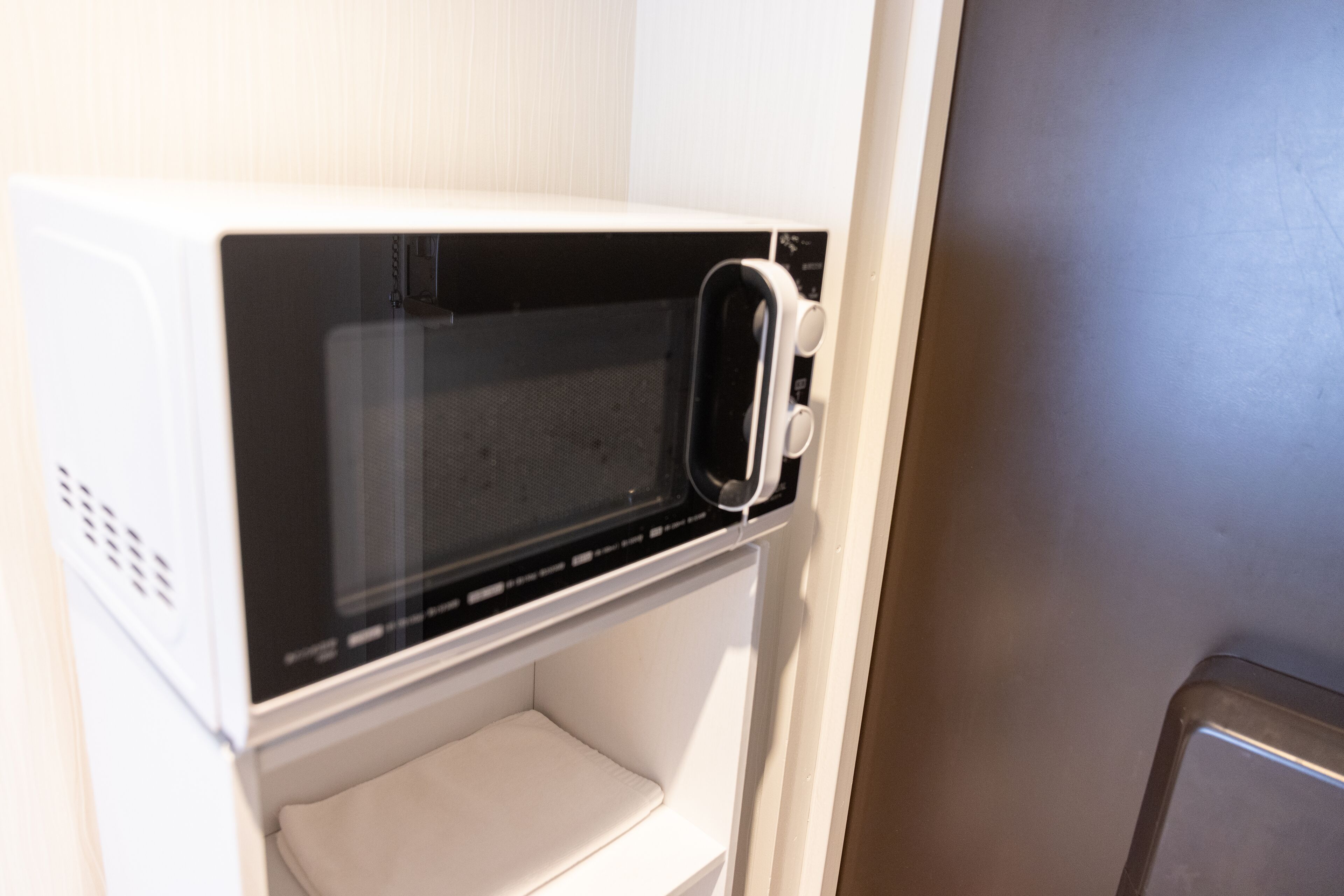 Un four à micro-ondes se trouve dans un coin cuisine, sous un meuble blanc.