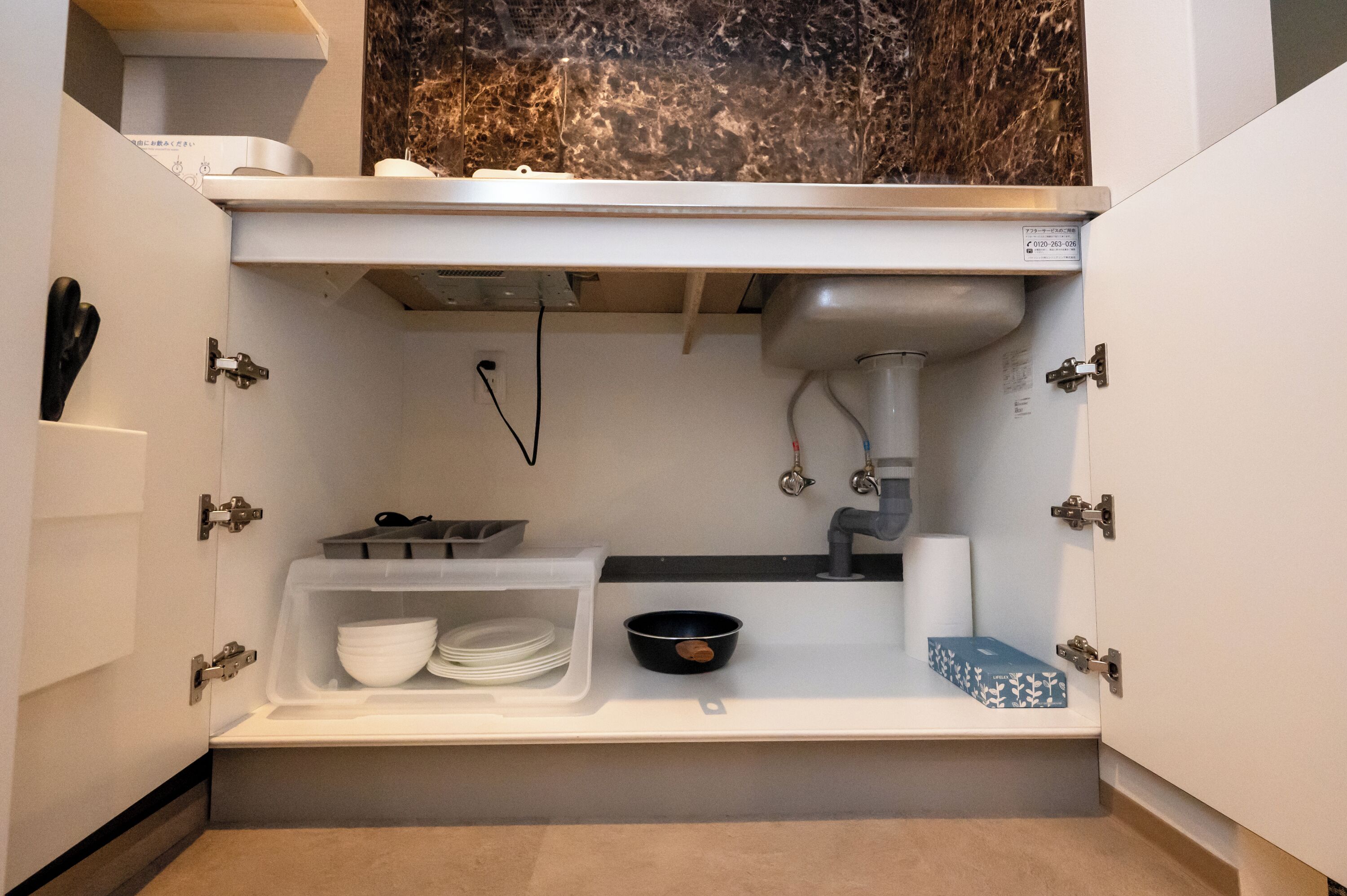 A compact kitchen with a built-in sink, storage compartments, and a marble backsplash.