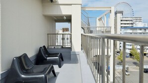 A balcony with black chairs, a railing, and a view of a Ferris wheel in the distance. - KIKU'S ROOM (Osaka)