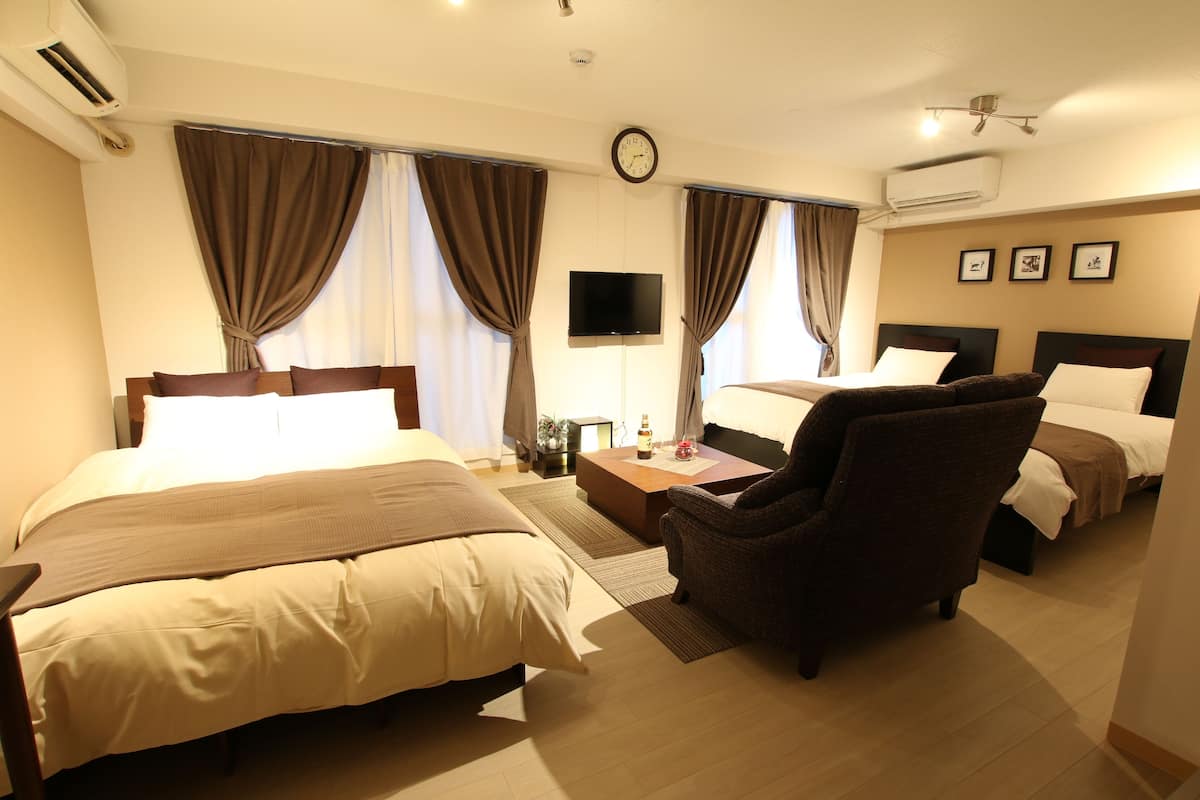 A hotel room with two beds, a flat-screen TV, a coffee table, and a chair.