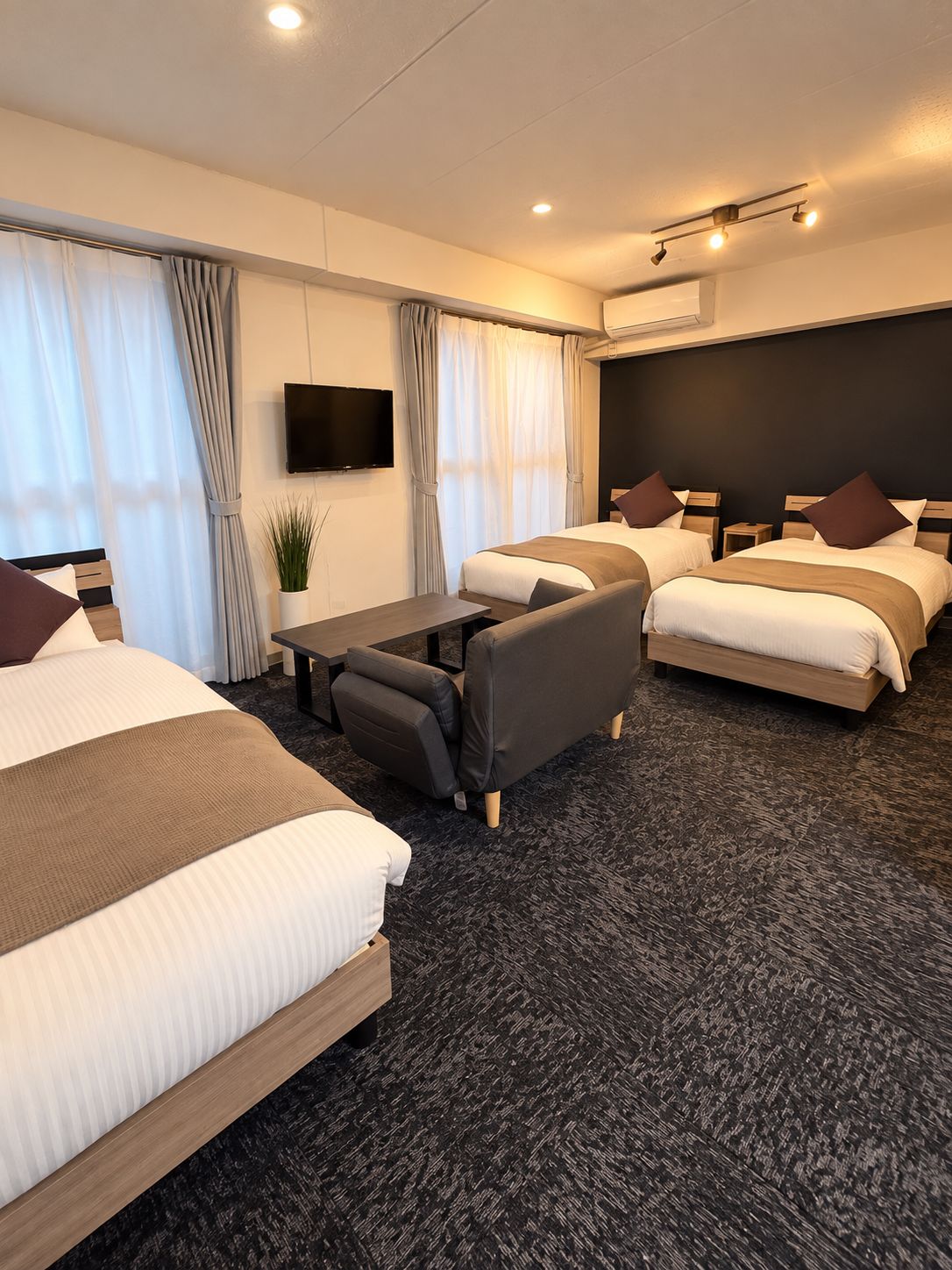 Habitación de hotel con dos camas, un sofá, un televisor de pantalla plana y una mesita.