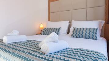 A hotel room with a large bed, two pillows, a bedside lamp, and rolled towels.