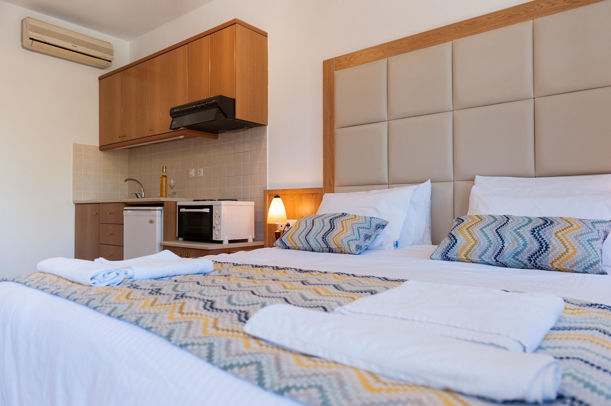 Une chambre d’hôtel avec un lit, une petite kitchenette et une tête de lit intégrée.