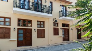 A two-story building with wooden doors and windows, a balcony with chairs, and a stone-paved street. - Pallazzo Fortezza (Rethymno)