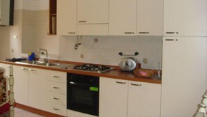 Una cocina con armarios blancos, estufa, fregadero y lavavajillas.