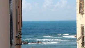 Vista costera con un edificio que domina el mar, con un balcón con barandilla y una farola.