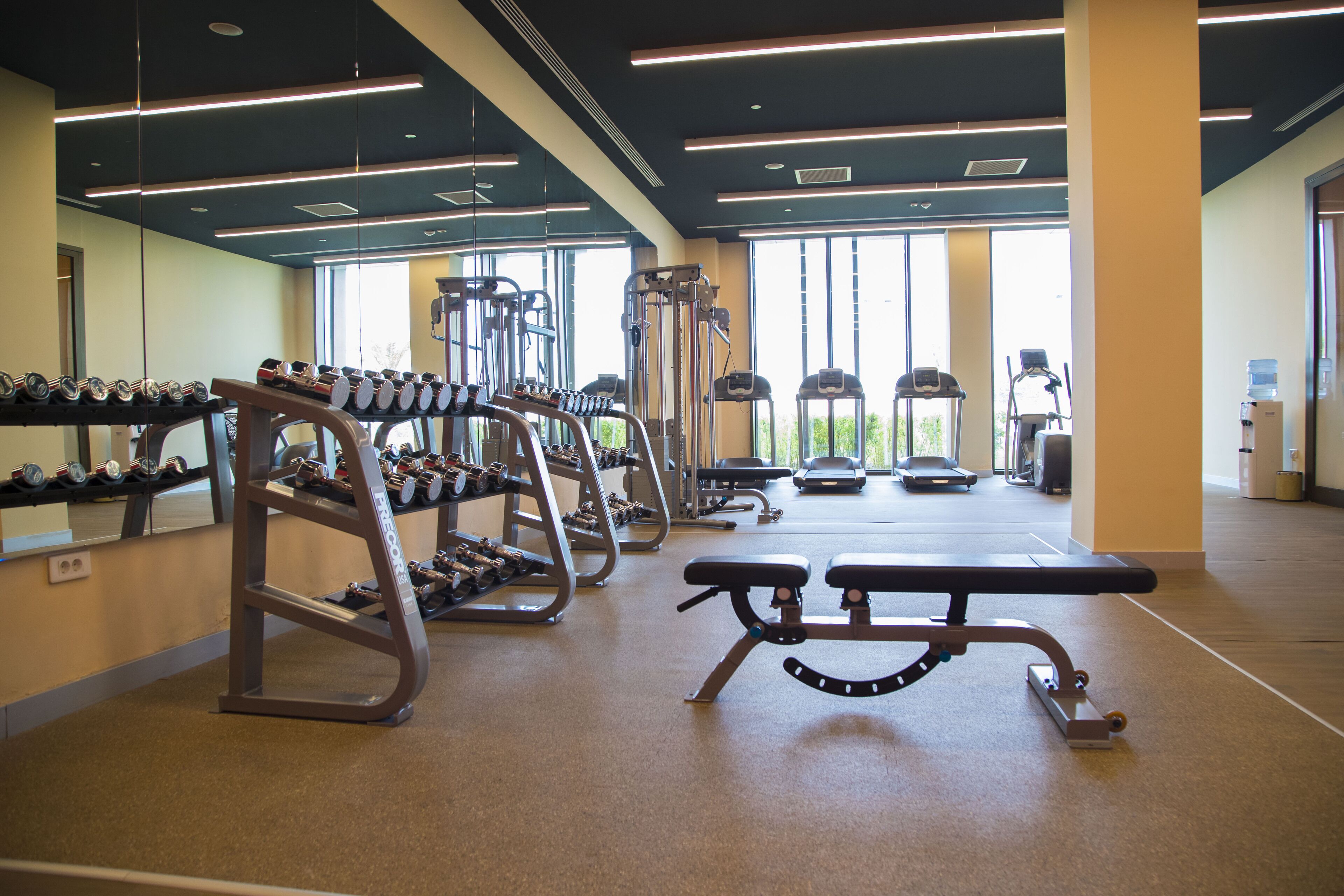 A gym with weight machines, benches, and dumbbells.
