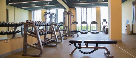 A gym with weight machines, benches, and dumbbells.