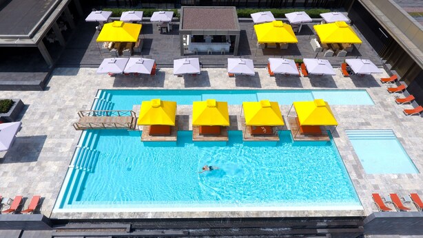 Un espace piscine aménagé sur le toit, avec plusieurs parasols jaunes et des chaises longues.