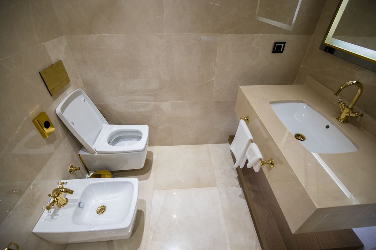 Un baño con inodoro, lavamanos y bañera, todo con accesorios dorados.