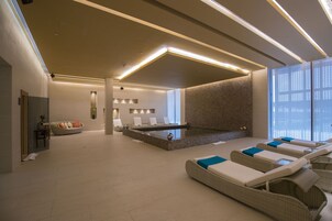 Una piscina techada, una piscina al aire libre, sombrillas