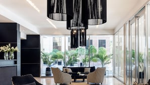 A modern living room with black sofas, a glass coffee table, and patterned chairs.