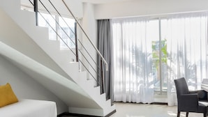 A modern living room with a staircase, a sofa, a coffee table, and a chair.