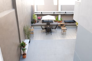 A patio area with a table and chairs, surrounded by potted plants and a bench. - DuMont Lisbon Guesthouse (Lisbon)