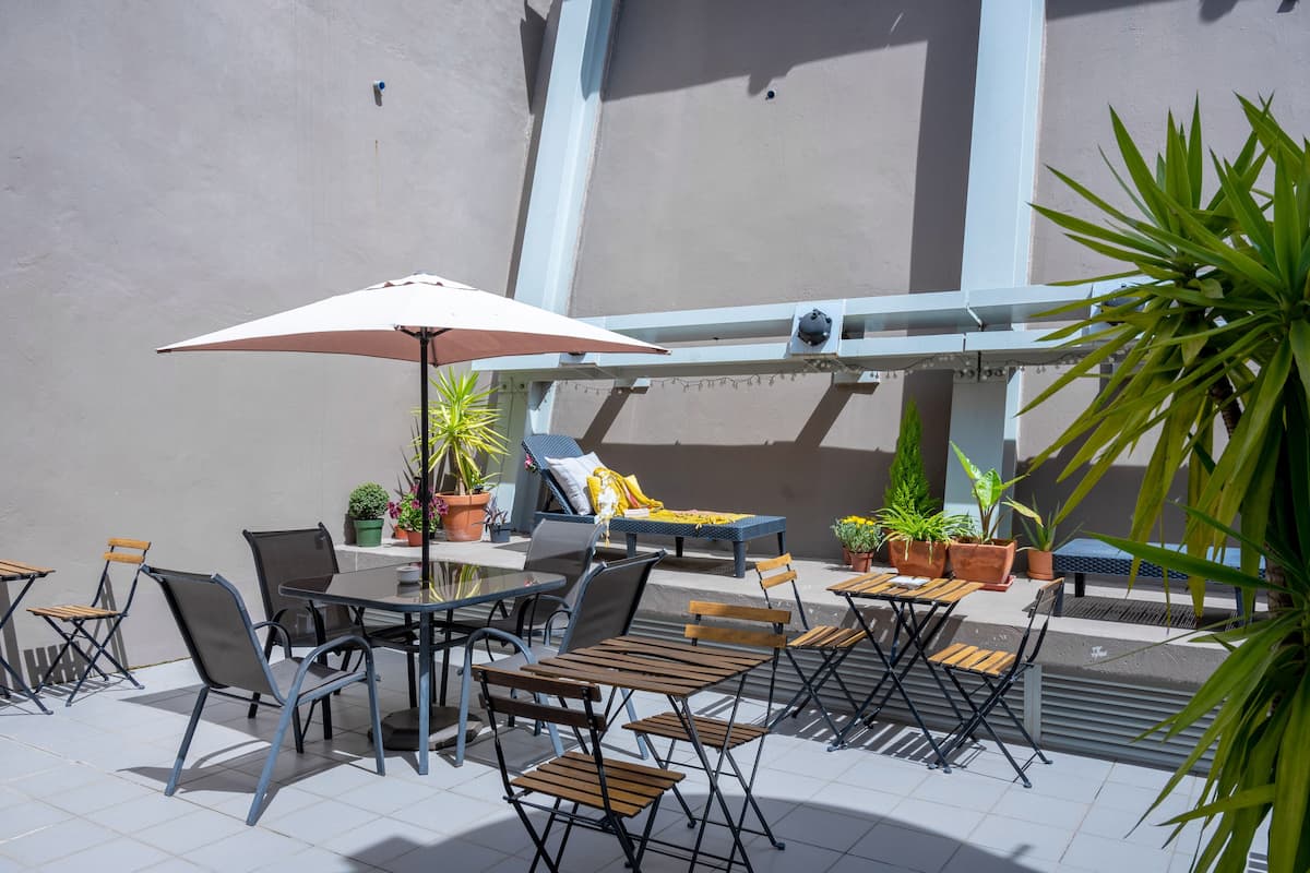 An outdoor patio area with tables and chairs, potted plants, and a seating area with a bench and cushions.
