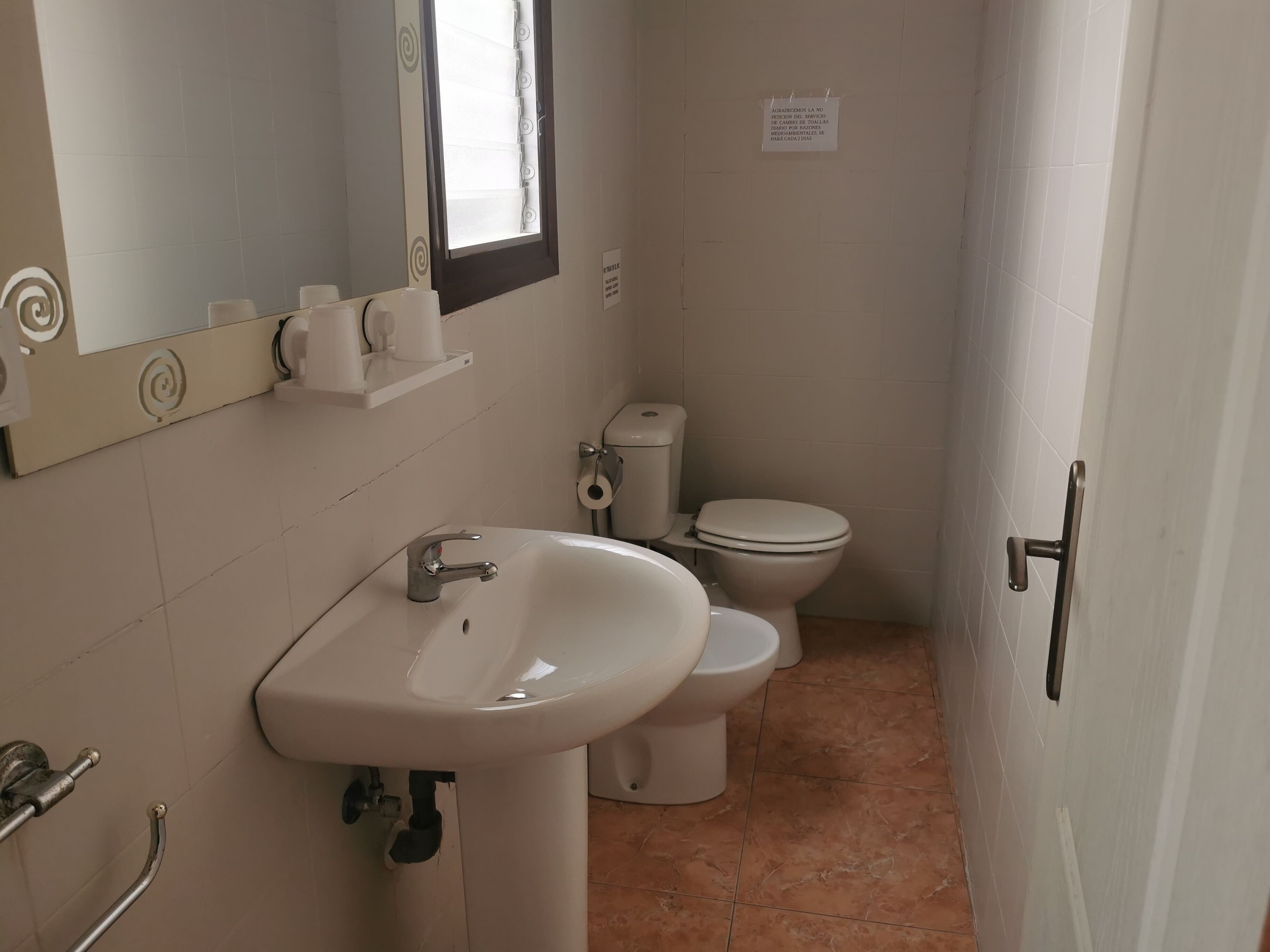 Een badkamer met een wastafel, toilet en spiegel.