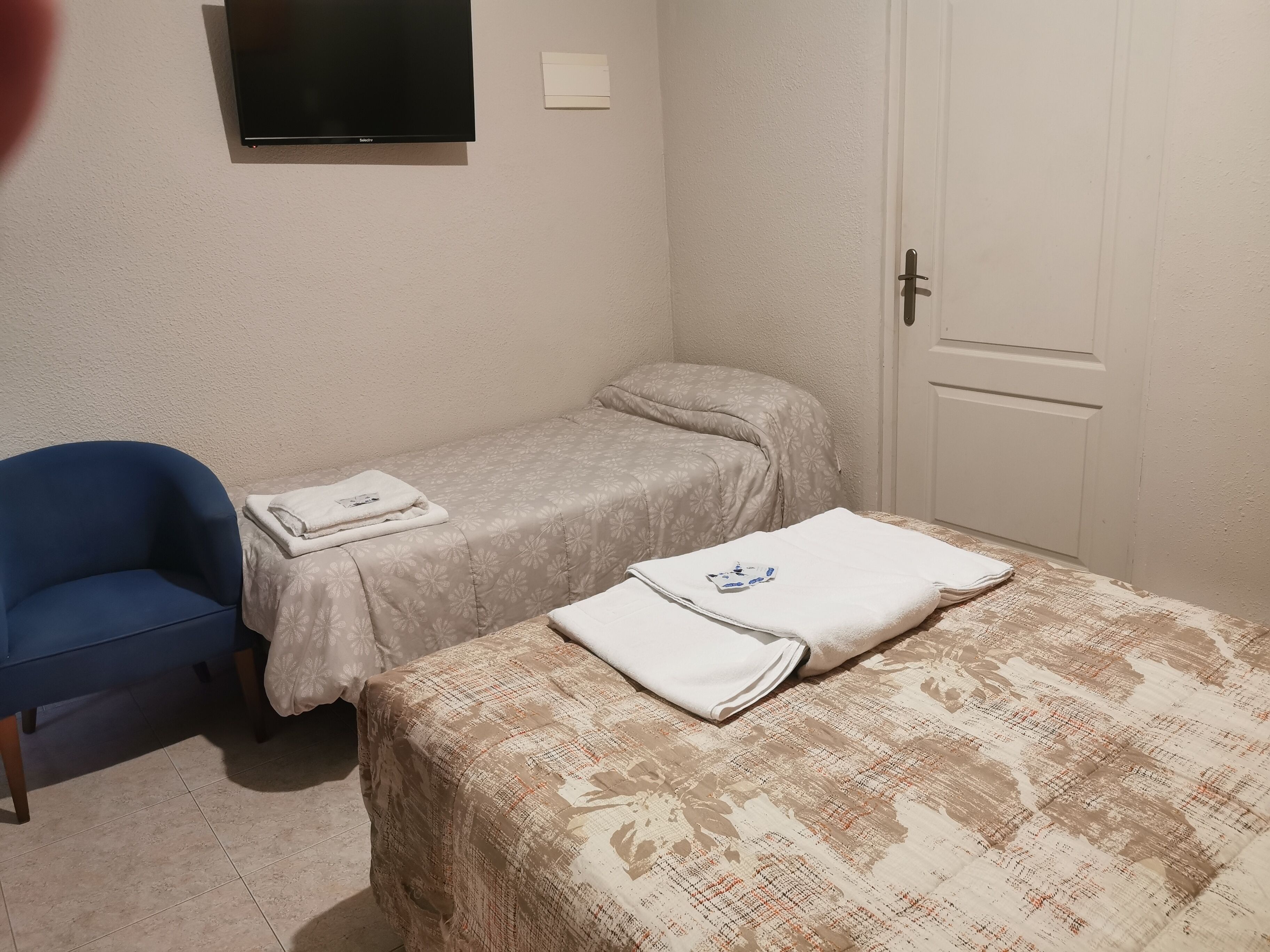 Una habitación pequeña y sencilla con una cama, una silla y una puerta.
