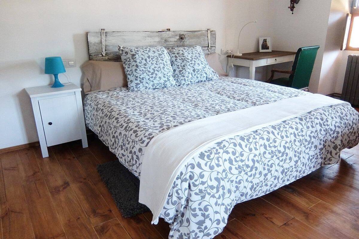 Una camera da letto con un letto, un comodino, una scrivania e una sedia.