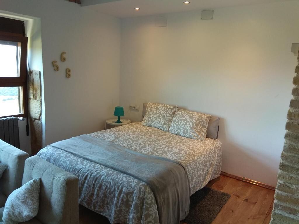 Une chambre à coucher avec un lit, une table de chevet, une lampe et une fenêtre.