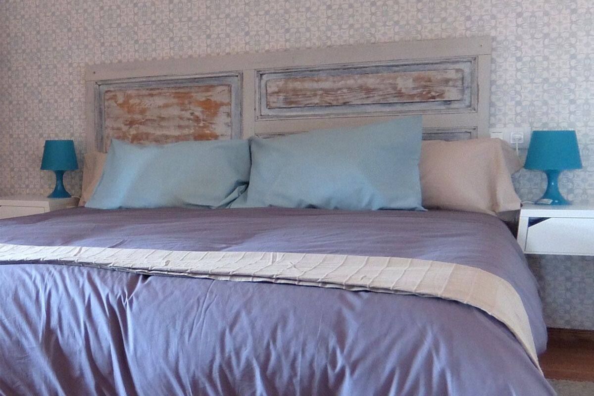 Una camera da letto con un letto, due comodini e una testiera dal sapore vintage.