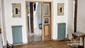 A rustic room with exposed wooden beams, a wooden door, and two vintage-style radiators. - La Madriguera de Tomaso (Valle de Yerri)