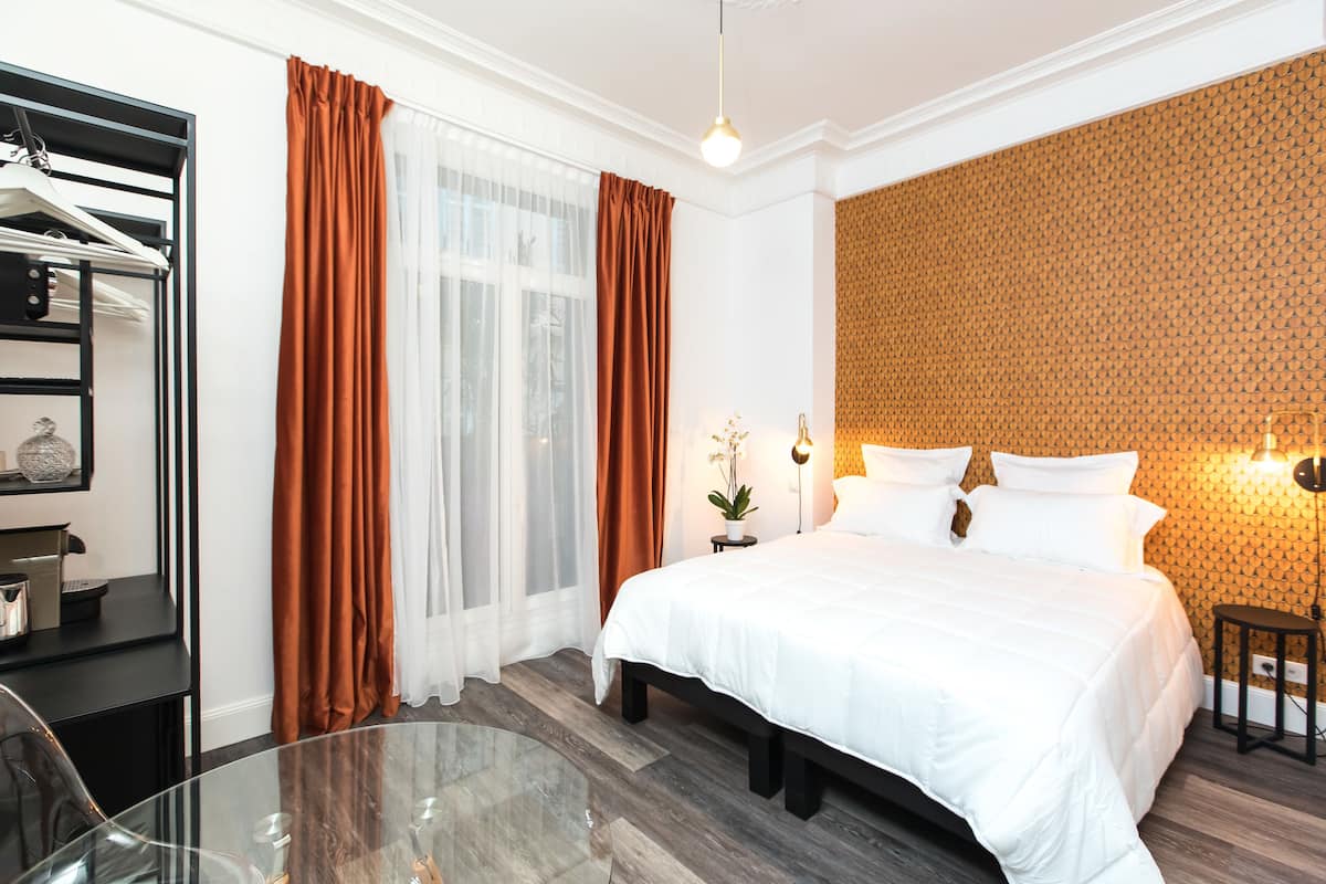 Habitación de hotel con cama, mesita de vidrio, armario y pared con diseño.
