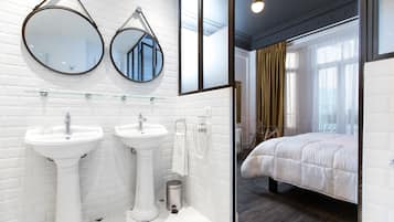 A modern bathroom with two sinks, a mirror, and a glass shower enclosure.