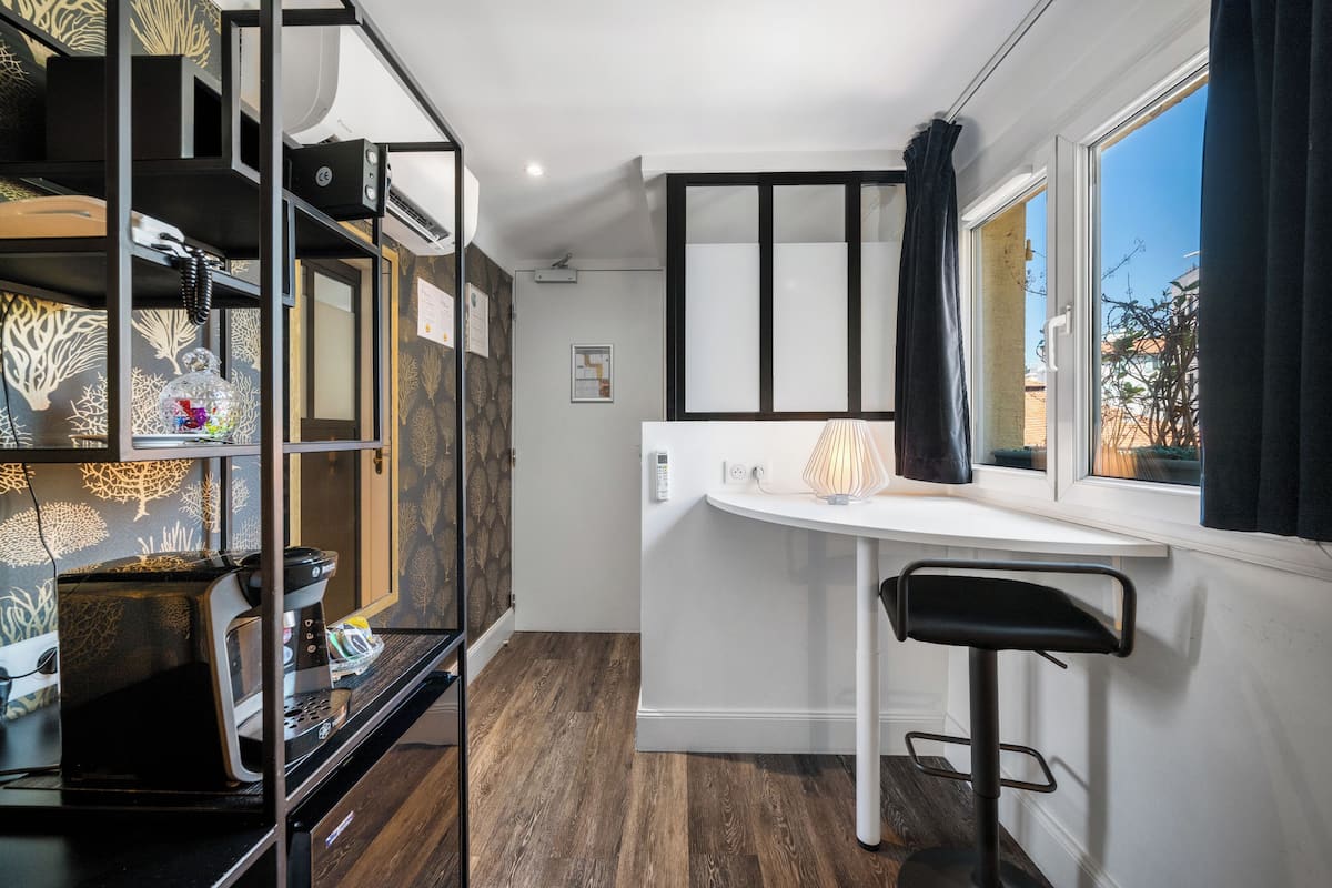 Una cocina compacta con horno integrado, cafetera y ventana con cortinas.