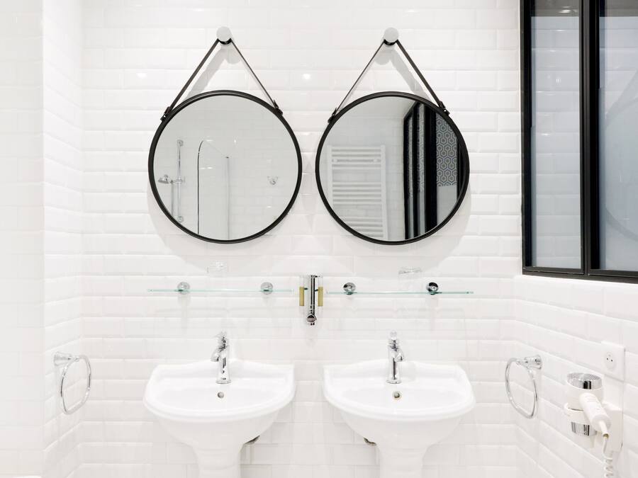 Un baño moderno con dos lavamanos, un inodoro y un bidé, todo en color blanco.