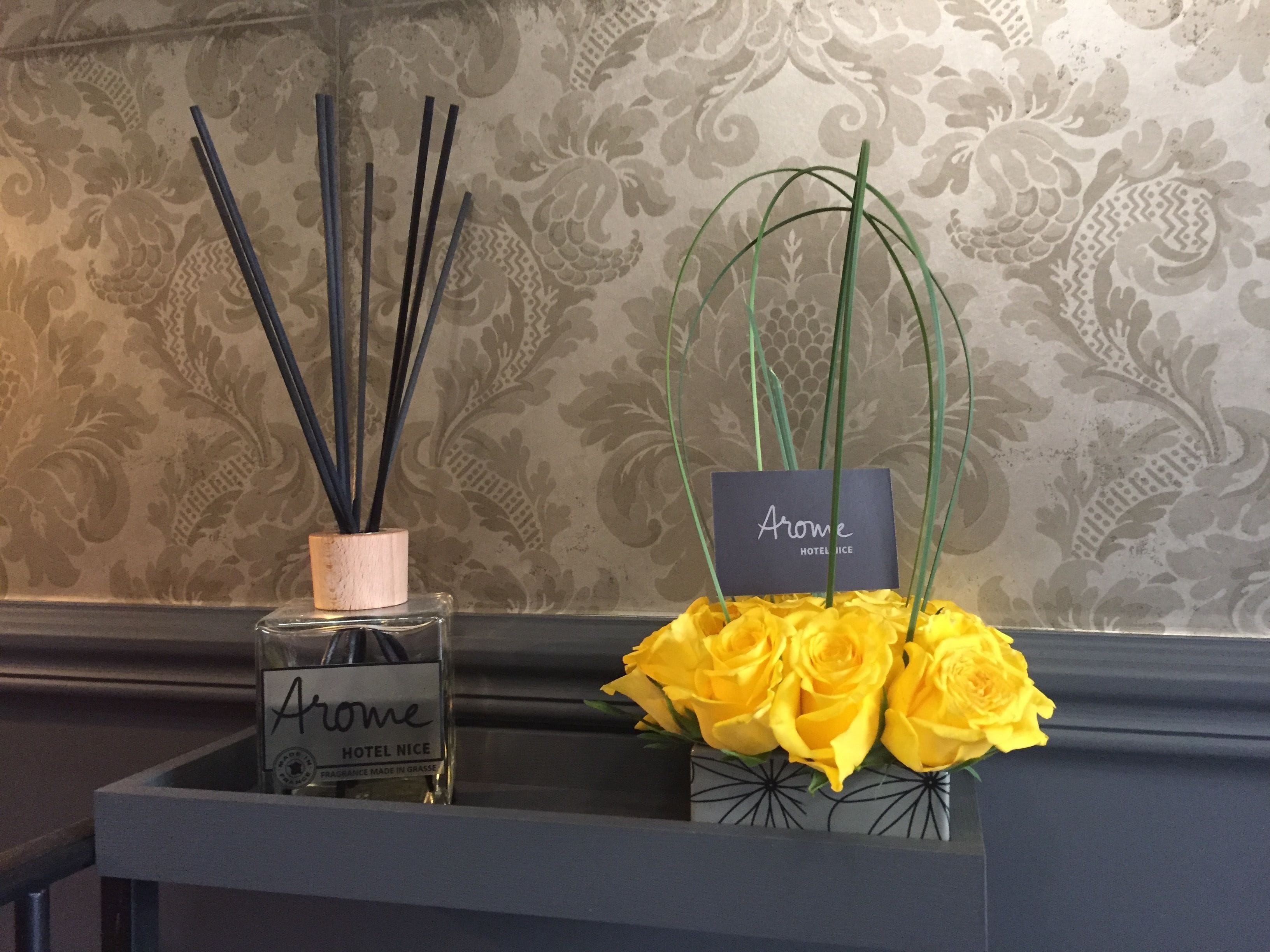 A bottle of Arome Hotel Nice fragrance and a bouquet of yellow roses.
