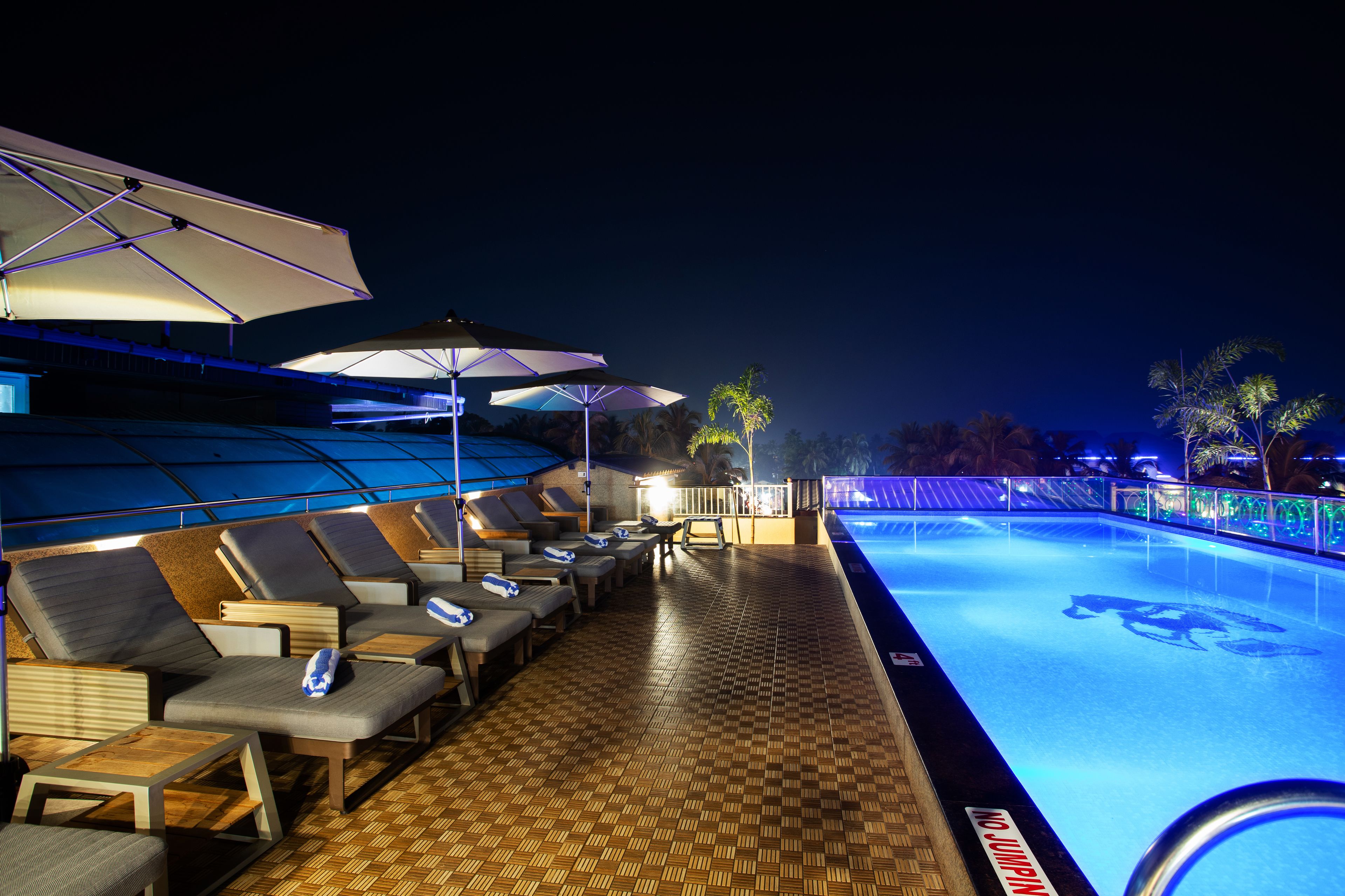 A poolside area with lounge chairs, umbrellas, and a pool.