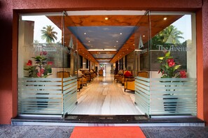 A hotel entrance with a glass facade, a red carpet, and a view of the interior seating area. - The Avenue Calangute (Calangute)