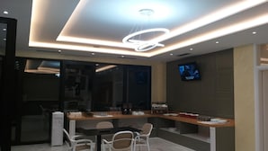 A modern kitchen with a dining area, a built-in oven, and a television mounted on the wall. - Hotel Roalb (Orikum)