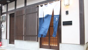 A traditional Japanese building with a wooden sliding door and a blue and white curtain. - The Residence Shin (Kyoto)
