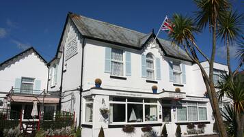 Traditional Swiss Cottage Hotel features a classic front entrance with a canopy and potted plants.