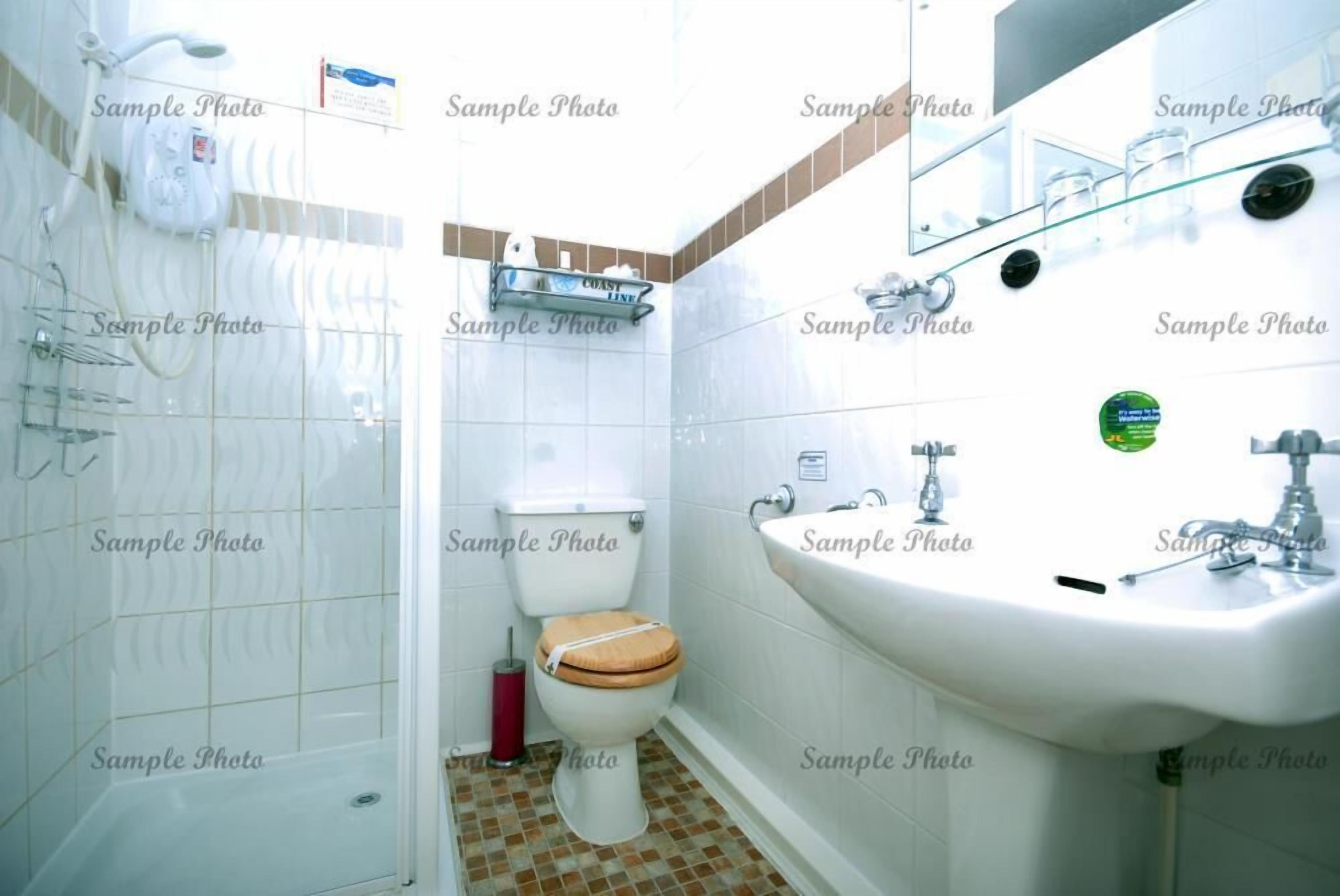 A bathroom with a toilet, sink, and shower.
