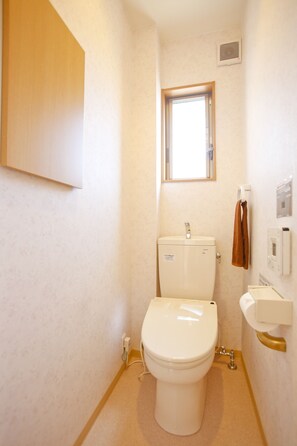 A small, well-lit bathroom with a toilet, sink, and window. - Private Residence Fushimi Inari (Kyoto)
