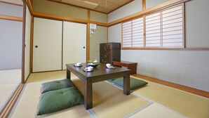 Ein traditioneller japanischer Raum mit Tatami-Bodenbelag, einem niedrigen Holztisch mit Tee-Service und Schiebetüren.