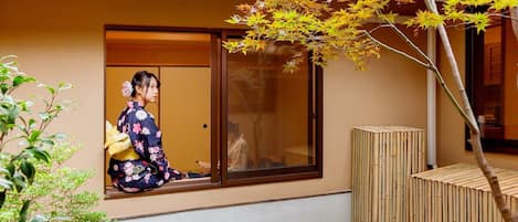 A traditional Japanese room with tatami flooring, sliding doors, and a view of a garden.