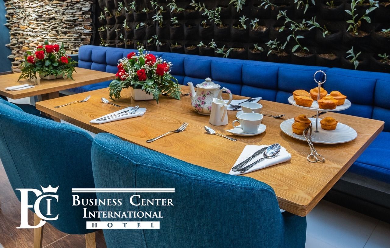 Un comedor con mesas de madera, asientos tapizados en azul y centros de mesa con flores.