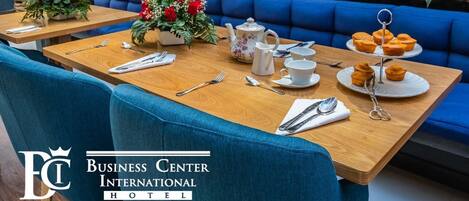 Un comedor con mesas de madera, asientos tapizados en azul y centros de mesa con flores.