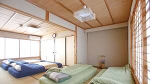 A traditional Japanese-style room with tatami flooring, two tatami mats with bedding, a shoji screen, and a ceiling fan. - Private Residence Shijo-Karasuma (Kyoto)