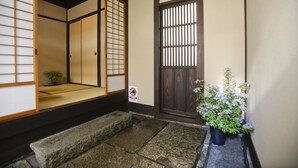 A traditional Japanese entrance with tatami flooring, a wooden door, and a potted plant. - Private Residence Shijo-Karasuma (Kyoto)